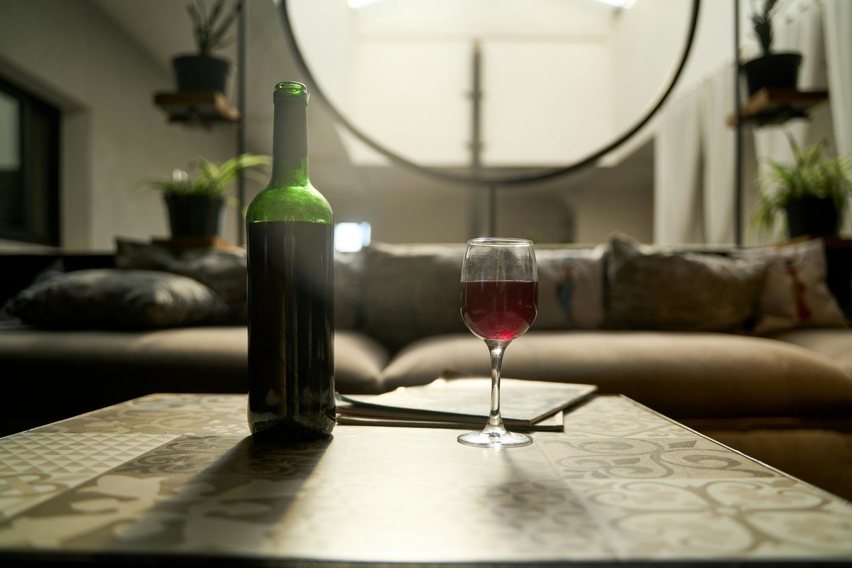Bouteille de vin rouge et verre servi sur une table basse dans un salon lumineux