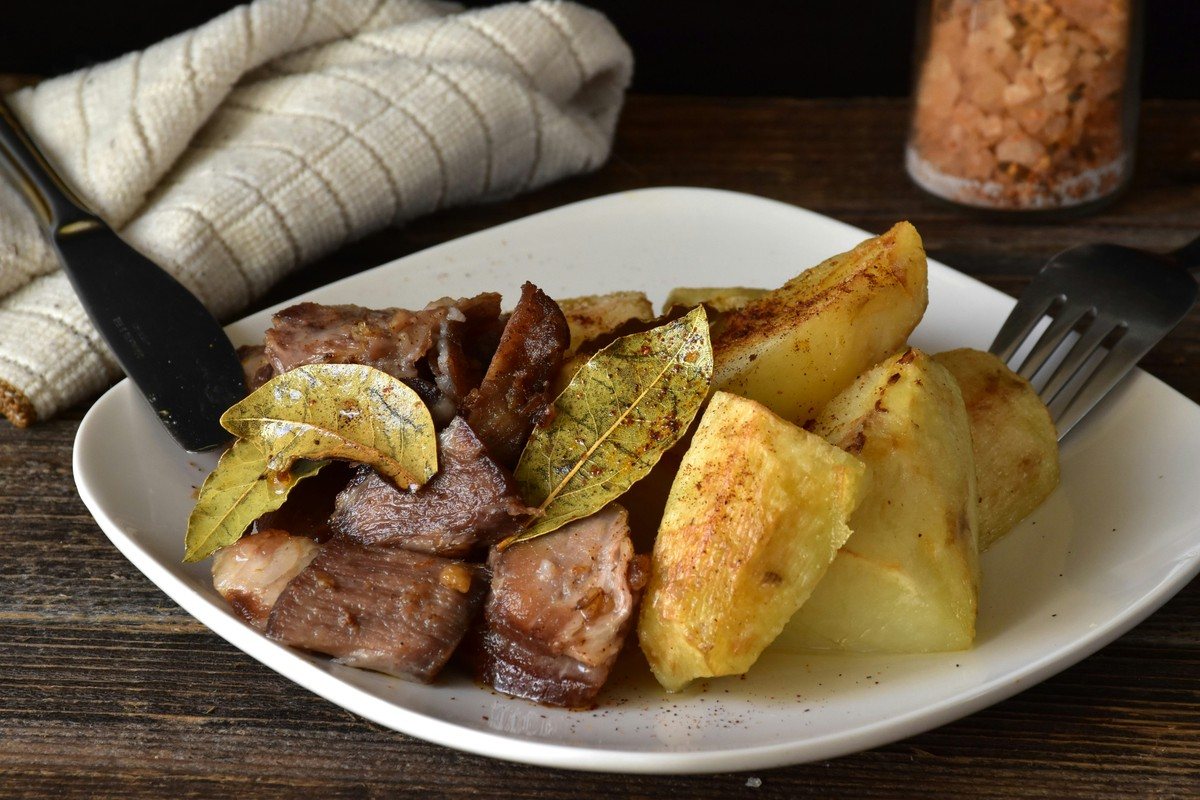Assiette de porc rôti avec des pommes de terre dorées et des feuilles de laurier