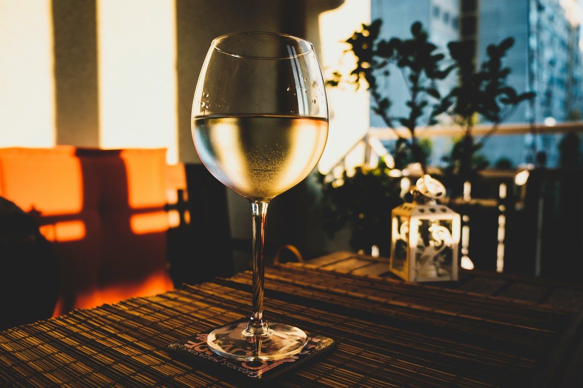 Verre de vin blanc couvert de buée posé sur une table, dans une lumière de fin de journée