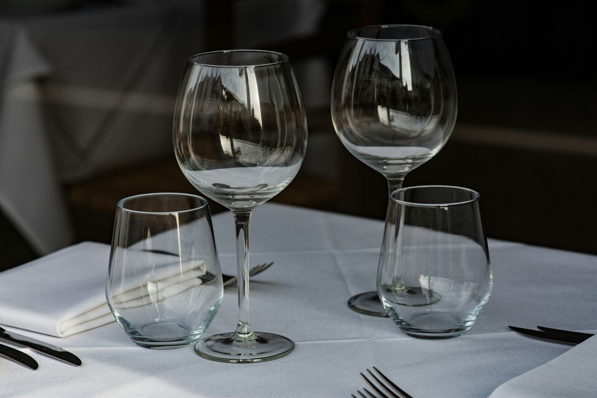 Deux verres à vin et deux gobelets parfaitement transparents sur une nappe blanche